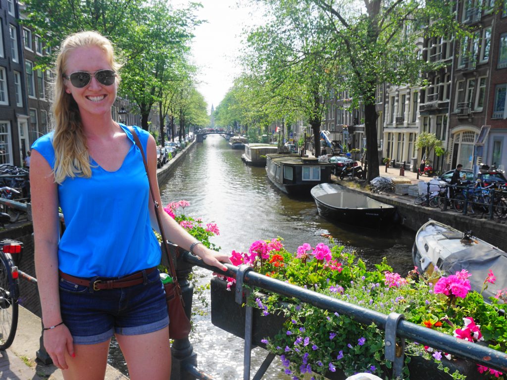 scenic Amsterdam canal with flowers, houseboats, bikes, and Melissa